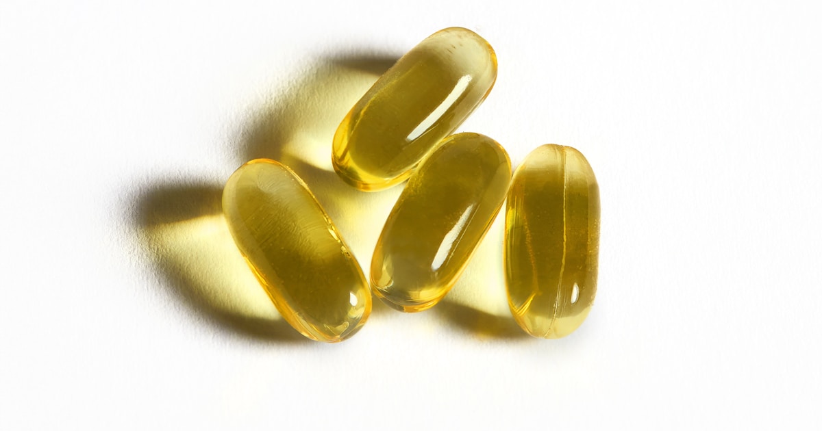 Cápsulas de vitamina E sobre superficie blanca